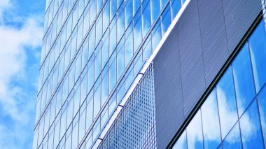 Mavi gökyüzü ve bulutlar modern ofis binasının camlarına yansıyor. Modern cam cephe. 