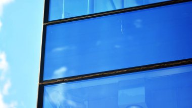 Mavi gökyüzü ve bulutlar modern ofis binasının camlarına yansıyor. Modern cam cephe. 