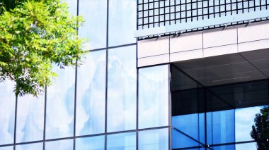 Mavi gökyüzü ve bulutlar modern ofis binasının camlarına yansıyor. Modern cam cephe. 