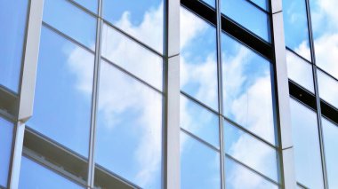 Glass and aluminum facade of a modern office building. View of futuristic architecture. Office building with cloud reflection on windows
