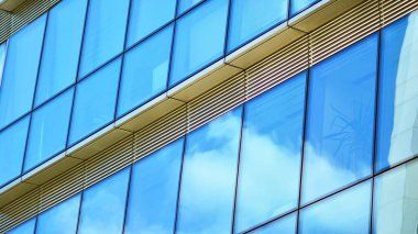 Yansıtıcı camlarla kaplı modern bir binanın cam kaplamalı dış cephesinin soyut yakın çekimi. Mimari soyut arkaplan. Cam duvar ve ön cephe ayrıntıları.