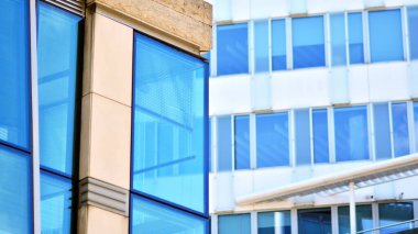 Yansıtıcı camlarla kaplı modern bir binanın cam kaplamalı dış cephesinin soyut yakın çekimi. Mimari soyut arkaplan. Cam duvar ve ön cephe ayrıntıları.