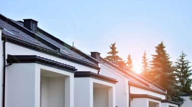 Yeni bir gelişim bölgesinde yeni bir aile evi. Modern görünüşlü bir ev. Arka planda güneş ışınları.