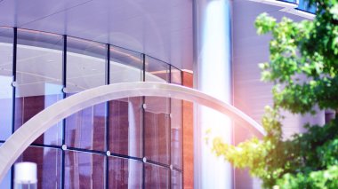 Çevre mimarisi. Yeşil ağaç ve cam ofis binası. Doğanın ve modernliğin ahengi. Modern ticari binanın yansıması güneş ışığıyla cam üzerine.. 