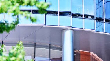 Çevre mimarisi. Yeşil ağaç ve cam ofis binası. Doğanın ve modernliğin ahengi. Modern ticari binanın yansıması güneş ışığıyla cam üzerine.. 