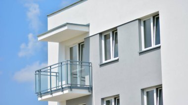 Mavi gökyüzü olan güneşli bir günde modern apartman binaları. Modern bir apartmanın ön cephesi. Güneş ışığıyla cam yüzey.