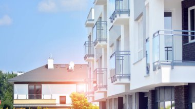 Mavi gökyüzü olan güneşli bir günde modern apartman binaları. Modern bir apartmanın ön cephesi. Güneş ışığıyla cam yüzey.