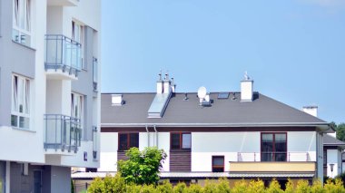 Mavi gökyüzü olan güneşli bir günde modern apartman binaları. Modern bir apartmanın ön cephesi. Güneş ışığıyla cam yüzey.