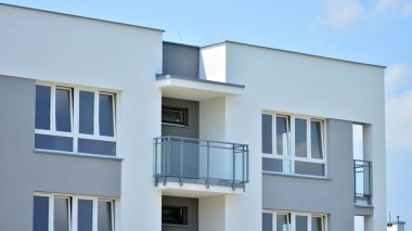 Mavi gökyüzü olan güneşli bir günde modern apartman binaları. Modern bir apartmanın ön cephesi. Güneş ışığıyla cam yüzey.