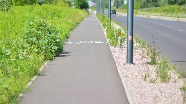 Şehir parkındaki yolda yeşil çimenli bisiklet yolu. Güvenli bisiklet konsepti.