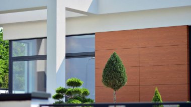 Tek bir aile binasının parçası. Pencereleri ve yeşili olan modern evin yan tarafında. Büyük lüks bir evin parçası..