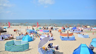 Miedzyzdroje, Polonya. 22 Temmuz 2021. Plaj manzarası. Sıcak yaz günlerinde turistler, güneşli yataklar ve rüzgarlıklar. Turistler yazın plajda güneşlenir, dinlenir ve denizde yüzerler..