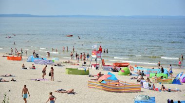 Miedzyzdroje, Polonya. 22 Temmuz 2021. Plaj manzarası. Sıcak yaz günlerinde turistler, güneşli yataklar ve rüzgarlıklar. Turistler yazın plajda güneşlenir, dinlenir ve denizde yüzerler..