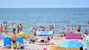 Miedzyzdroje, Polonya. 22 Temmuz 2021. Plaj manzarası. Sıcak yaz günlerinde turistler, güneşli yataklar ve rüzgarlıklar. Turistler yazın plajda güneşlenir, dinlenir ve denizde yüzerler..
