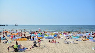 Miedzyzdroje, Polonya. 22 Temmuz 2021. Plaj manzarası. Sıcak yaz günlerinde turistler, güneşli yataklar ve rüzgarlıklar. Turistler yazın plajda güneşlenir, dinlenir ve denizde yüzerler..