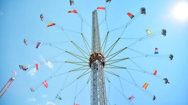 Szczecin, Polonya... 24 Temmuz 2021. Eğlence malzemeleri ve diğer eğlence tesisleriyle dolu bir lunapark. Mavi gökyüzüne karşı uçan atlıkarınca. 