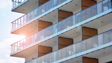 Cam balkonlu yeni apartman. Deniz kenarındaki modern mimari evler. Binanın ön cephesinde büyük camlar var..