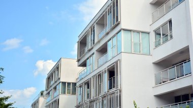 Geniş pencereli bir apartmanın modern beyaz cephesi. Modern tasarlanmış beton apartman manzarası.