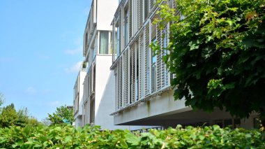 Geniş pencereli bir apartmanın modern beyaz cephesi. Modern tasarlanmış beton apartman manzarası.