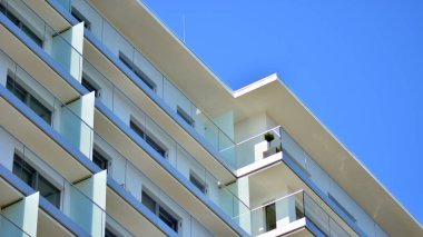 Cam balkonlu yeni apartman. Deniz kenarındaki modern mimari evler. Binanın ön cephesinde büyük camlar var..