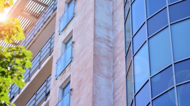 Yansıtıcı levhalar ve camlarla kaplı modern bir apartmanın dış cephesinin soyut görüntüsü..