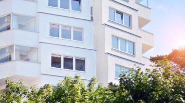 Geniş pencereli bir apartmanın modern beyaz cephesi. Modern tasarlanmış beton apartman manzarası.