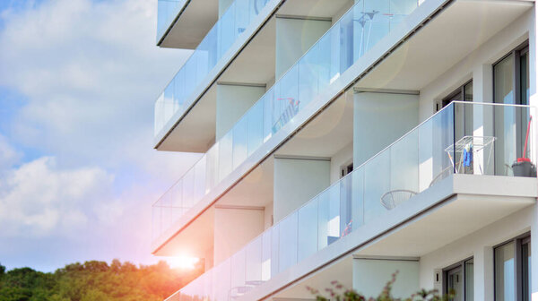 Новый жилой дом со стеклянными балконами. Современные архитектурные дома у моря. Большие стекла на фасаде здания.