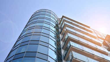 Yansıtıcı levhalar ve camlarla kaplı modern bir apartmanın dış cephesinin soyut görüntüsü..