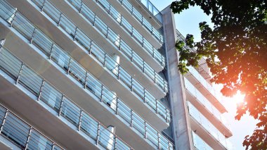 Cam balkonlu yeni apartman. Deniz kenarındaki modern mimari evler. Binanın ön cephesinde büyük camlar var..