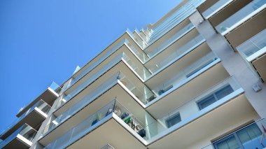 Cam balkonlu yeni apartman. Deniz kenarındaki modern mimari evler. Binanın ön cephesinde büyük camlar var..