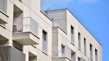 Mavi gökyüzü olan güneşli bir günde modern bir apartman. Modern bir apartmanın ön cephesi. Güneş ışığıyla kaplı cam yüzey..