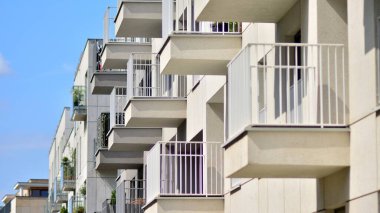 Mavi gökyüzü olan güneşli bir günde modern bir apartman. Modern bir apartmanın ön cephesi. Güneş ışığıyla kaplı cam yüzey..