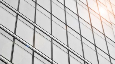 Modern mimari detaylar. Geometrik desenli modern cam cephe. Çağdaş şirket mimarisi. Kızıl güneş ufukta. Siyah ve beyaz tonlu görüntü.