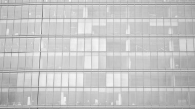 Modern mimari detaylar. Geometrik desenli modern cam cephe. Çağdaş şirket mimarisi. Kızıl güneş ufukta. Siyah ve beyaz tonlu görüntü.