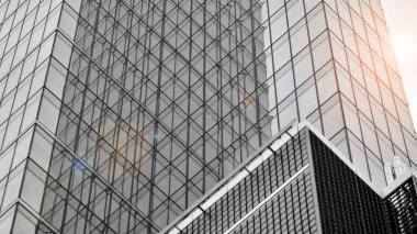 Modern mimari detaylar. Geometrik desenli modern cam cephe. Çağdaş şirket mimarisi. Kızıl güneş ufukta. Siyah ve beyaz tonlu görüntü.