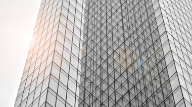 Modern mimari detaylar. Geometrik desenli modern cam cephe. Çağdaş şirket mimarisi. Kızıl güneş ufukta. Siyah ve beyaz tonlu görüntü.