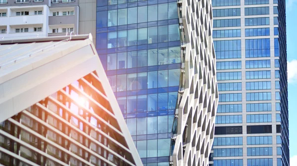 Facade texture of a glass mirrored office building. Fragment of the facade. Bottom view of modern skyscrapers in business district in evening light at sunset with lens flare filter effect.