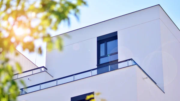 Ecological housing architecture. A modern residential building in the vicinity of trees. Ecology and green living in city, urban environment concept. Modern apartment building and green trees.