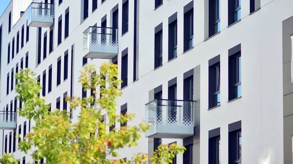 Ecological housing architecture. A modern residential building in the vicinity of trees. Ecology and green living in city, urban environment concept. Modern apartment building and green trees.