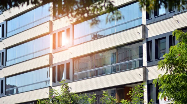 Ecological housing architecture. A modern residential building in the vicinity of trees. Ecology and green living in city, urban environment concept. Modern apartment building and green trees.