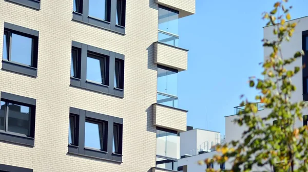 Ecological housing architecture. A modern residential building in the vicinity of trees. Ecology and green living in city, urban environment concept. Modern apartment building and green trees.