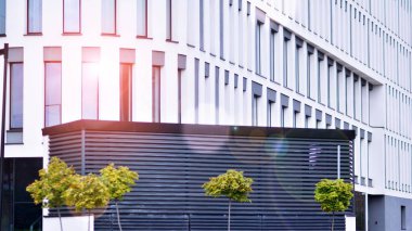 Geometrik desenli modern cam cephe. Çağdaş şirket mimarisi. Ufukta kızıl güneş, Bokeh güneş patlaması. 