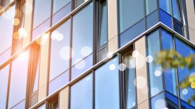 Geometrik desenli modern cam cephe. Çağdaş şirket mimarisi. Ufukta kızıl güneş, Bokeh güneş patlaması. 