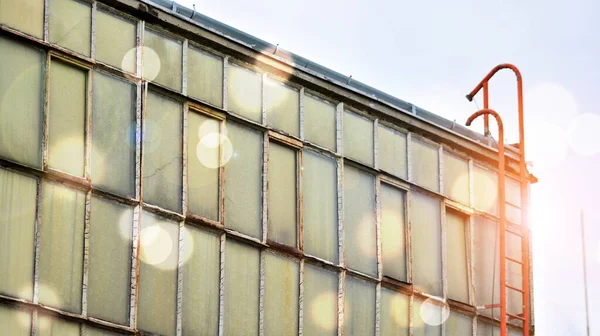 View of abandoned industrial complex. Former factory. Damaged industrial halls. Red sun on horizon, bokeh solar flare