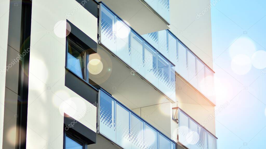 Modern apartment building on a sunny day. Architectural details and facade of a modern apartment building. Red sun on horizon, bokeh solar flare. 