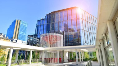 Modern luxury office building.The structure features a glass and concrete walls, showcasing contemporary architecture. The green surroundings of office buildings. Trees and shrubs in the city.