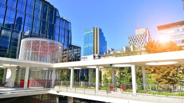Modern luxury office building.The structure features a glass and concrete walls, showcasing contemporary architecture. The green surroundings of office buildings. Trees and shrubs in the city.