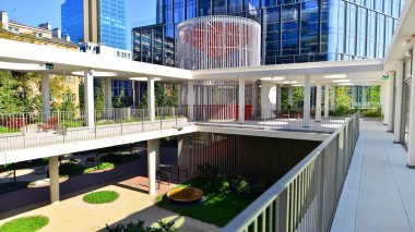 Modern luxury office building.The structure features a glass and concrete walls, showcasing contemporary architecture. The green surroundings of office buildings. Trees and shrubs in the city.