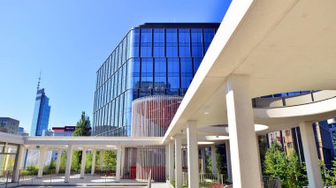 Modern luxury office building.The structure features a glass and concrete walls, showcasing contemporary architecture. The green surroundings of office buildings. Trees and shrubs in the city.