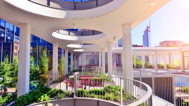 Modern luxury office building.The structure features a glass and concrete walls, showcasing contemporary architecture. The green surroundings of office buildings. Trees and shrubs in the city.